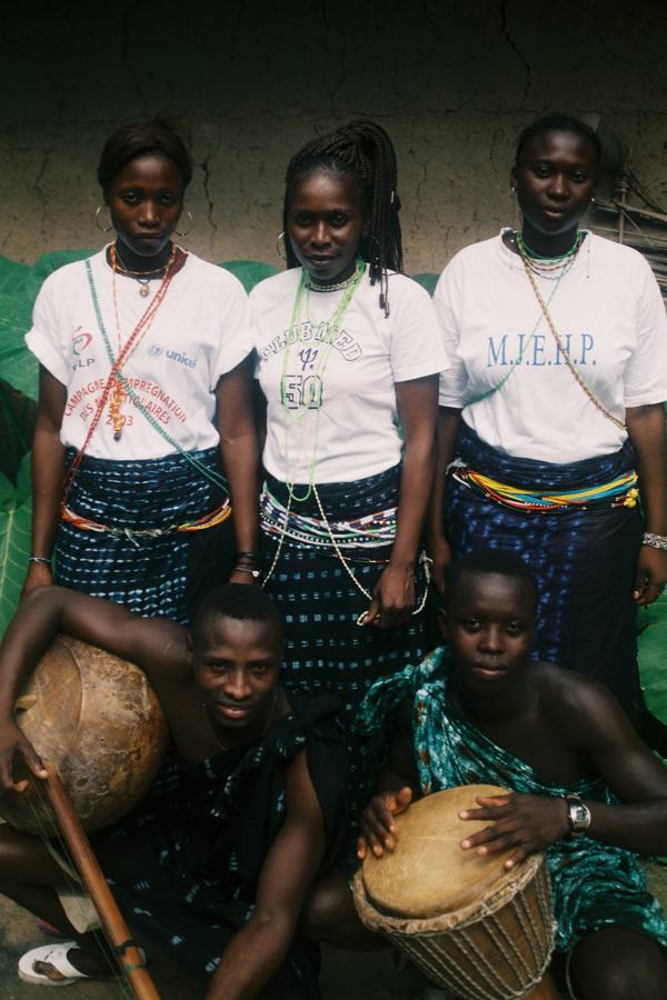 A group in white T-shirts and wraps with drums